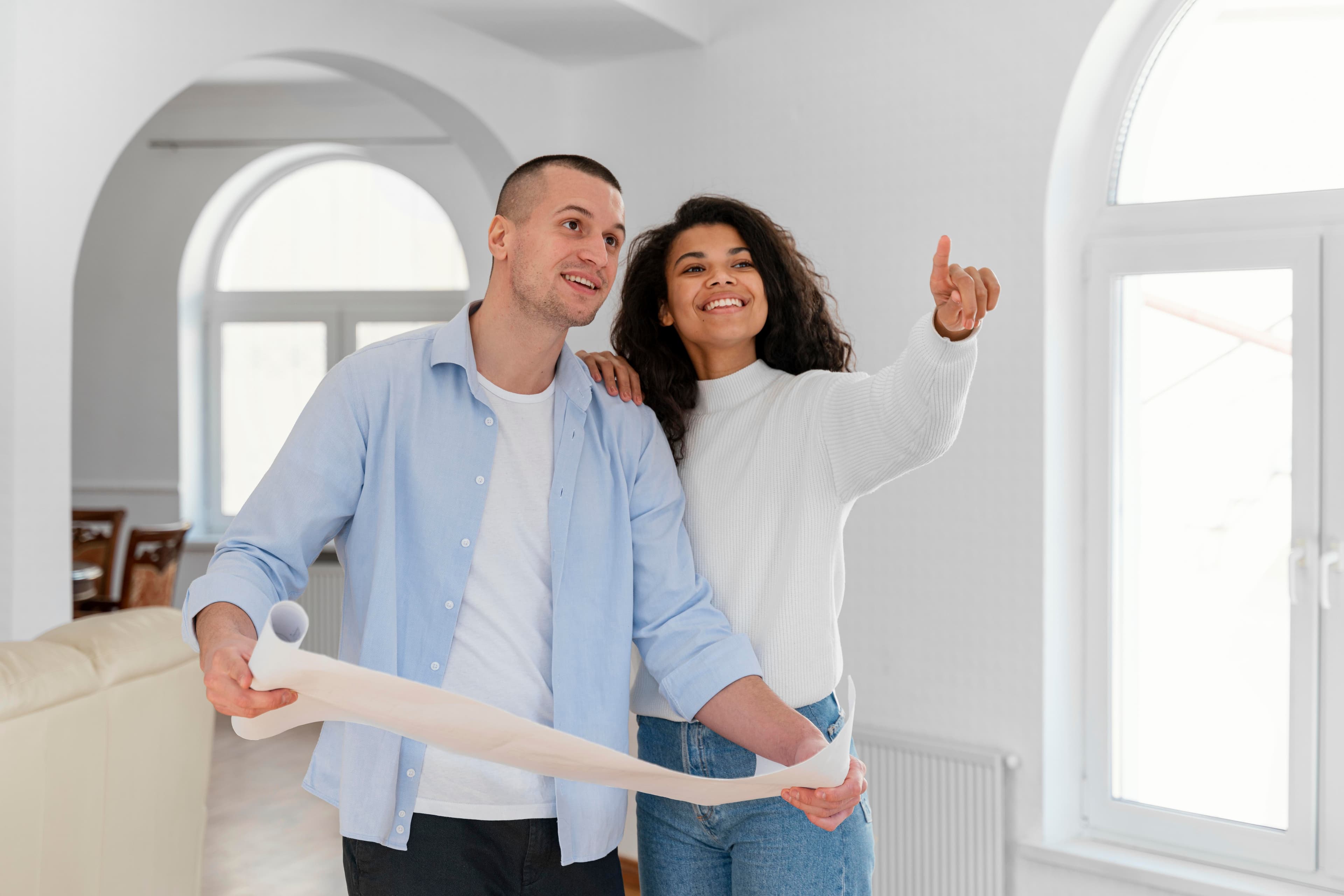 A couple walking through a home holding the floor plans